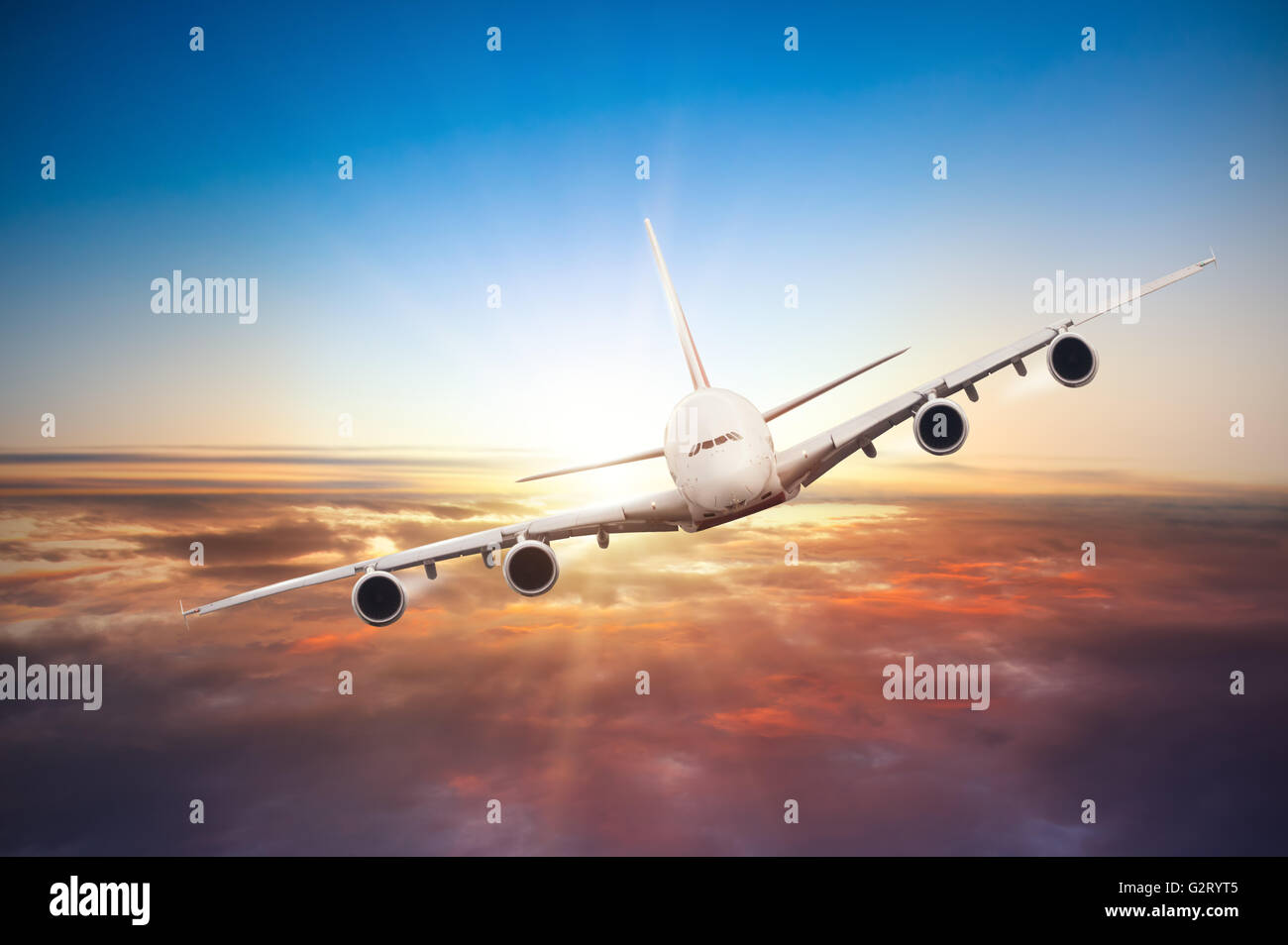 El avión comercial volando por encima de las nubes en la dramática luz del atardecer Foto de stock