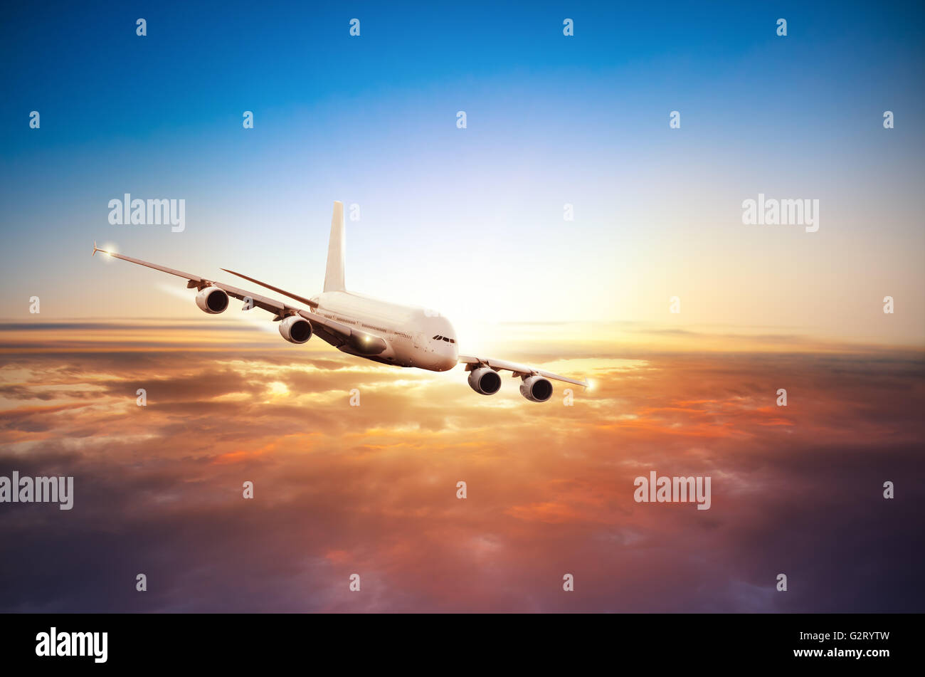 El avión comercial volando por encima de las nubes en la dramática luz del atardecer Foto de stock