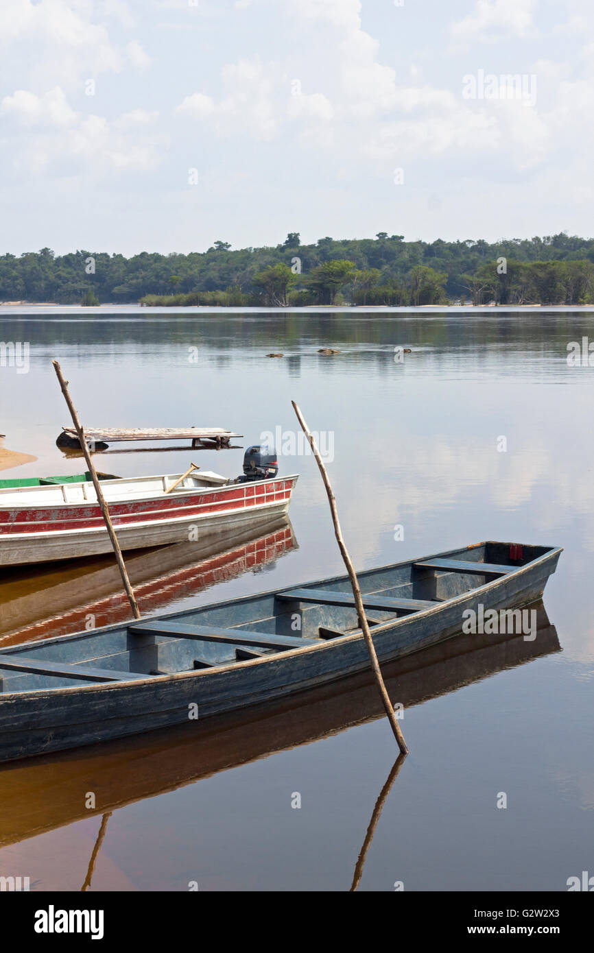 Viejos barcos de madera amarrados a la orilla del río Amazonas en Brasil. El cielo se refleja en el agua. Foto de stock