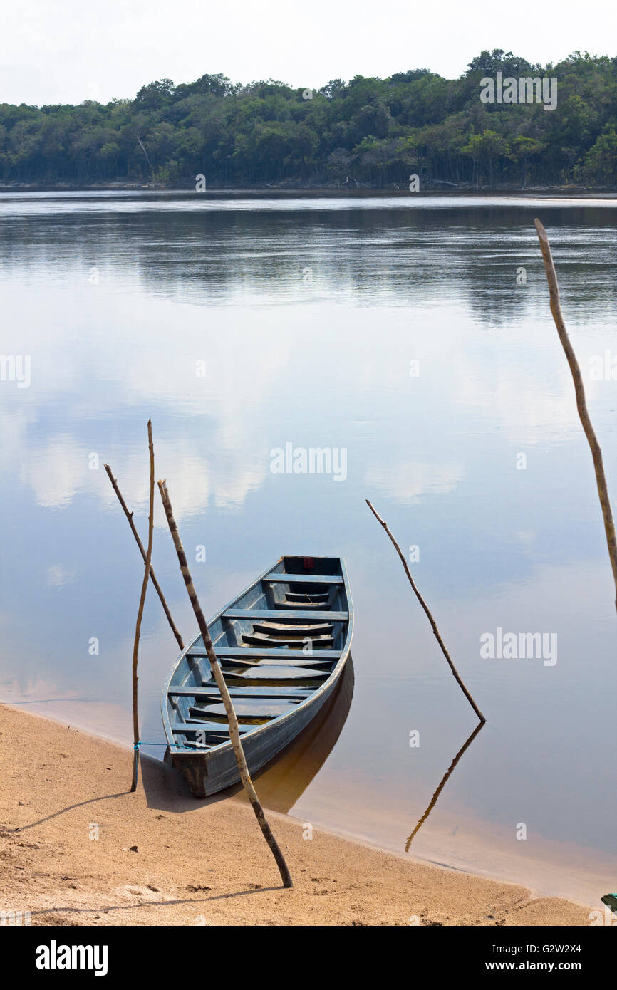 Viejo barco de madera amarrados a la orilla del río Amazonas en Brasil. El cielo se refleja en el agua. Foto de stock