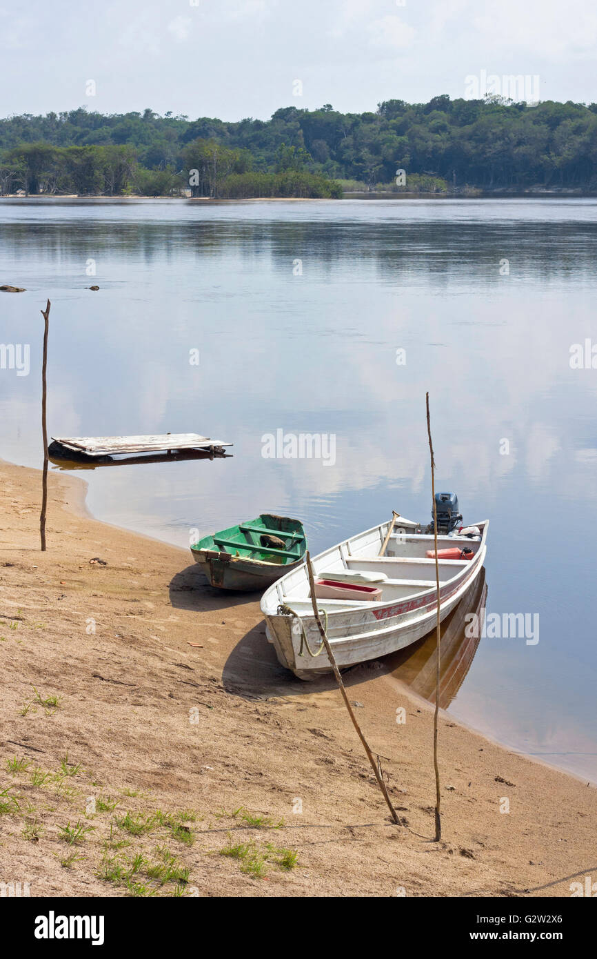 Viejos barcos de madera amarrados a la orilla del río Amazonas en Brasil. El cielo se refleja en el agua. Foto de stock