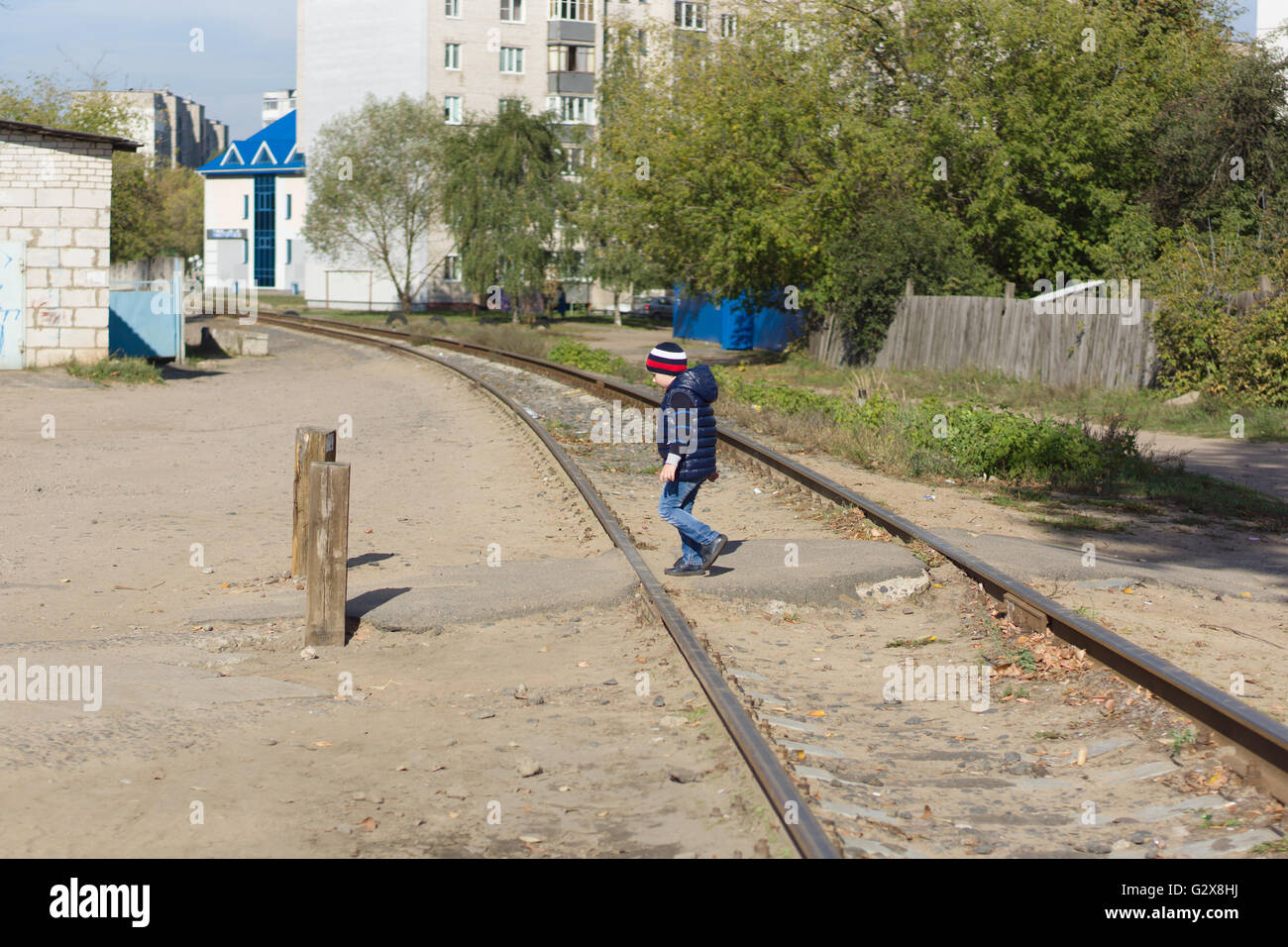El muchacho transfiere las vías de ferrocarril ubicada en la ciudad Foto de stock