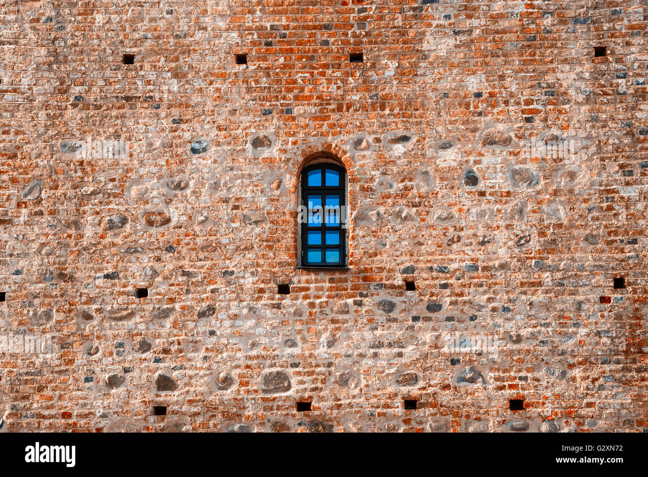 Ventana arqueada en una pared de castillo de ladrillo rojo envejecido Foto de stock