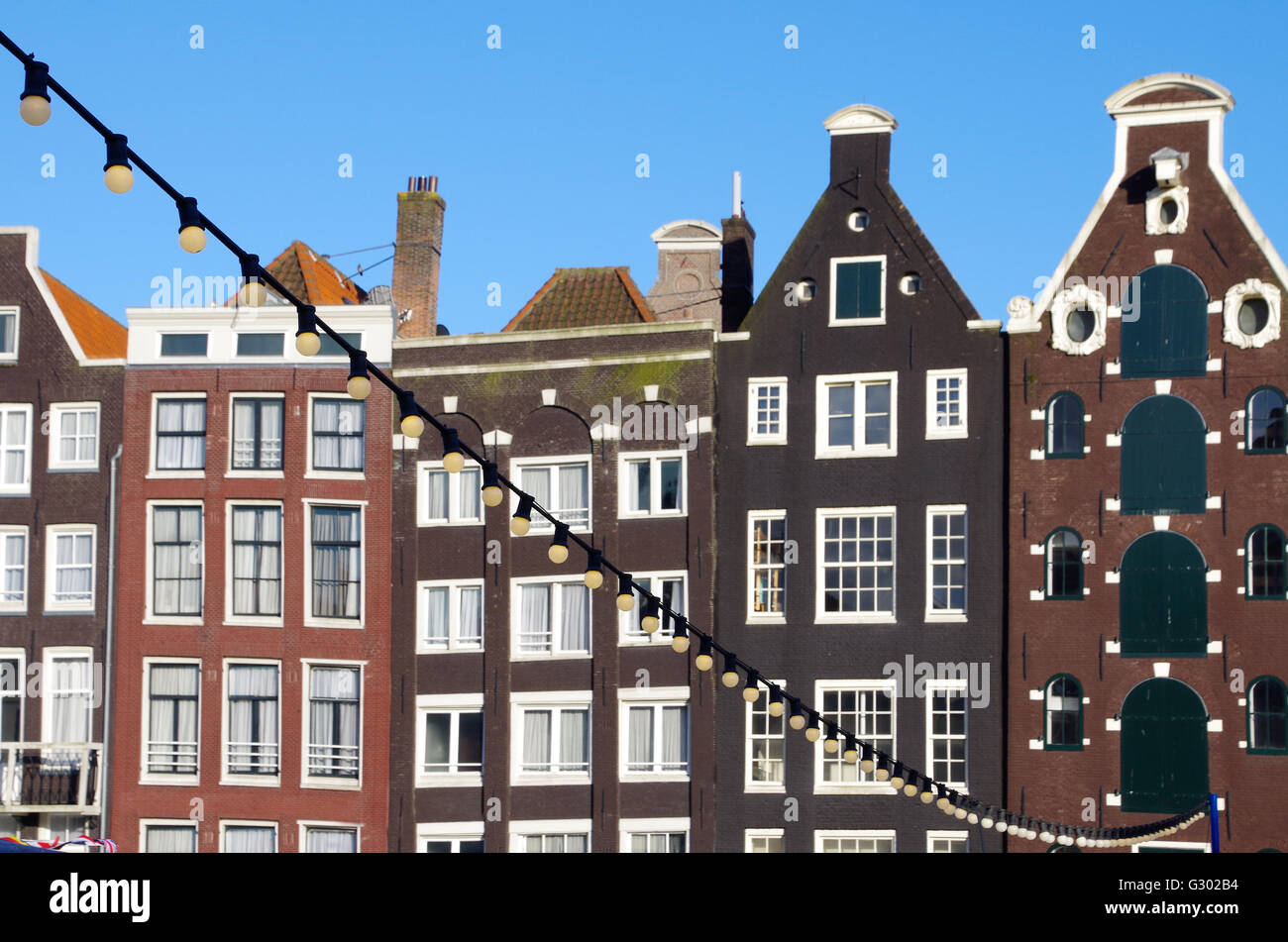 Luces de cadena globo colgaba sobre un canal en Amsterdam Amsterdam con típicas casas en el fondo Foto de stock