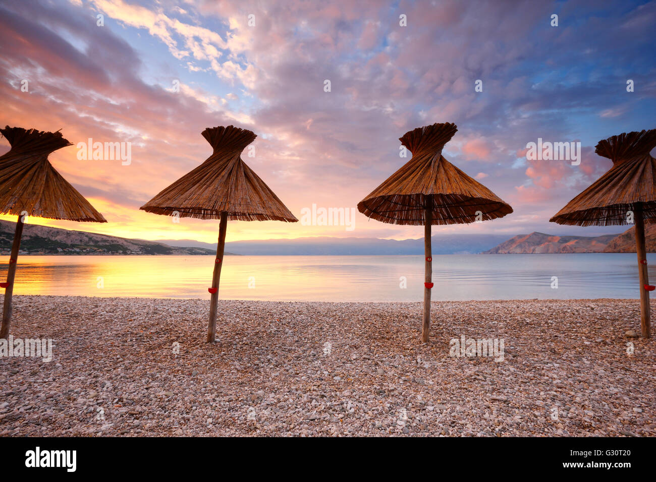 Sombrillas de paja en la playa de Baska en la isla de Krk Foto de stock