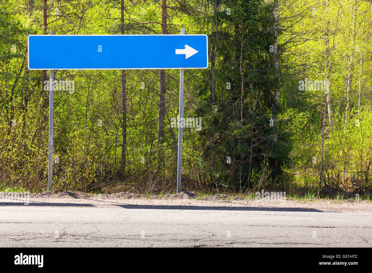 Señal de carretera azul, cerca de la autopista con el lugar de destino en blanco el nombre y la dirección de la flecha blanca Foto de stock