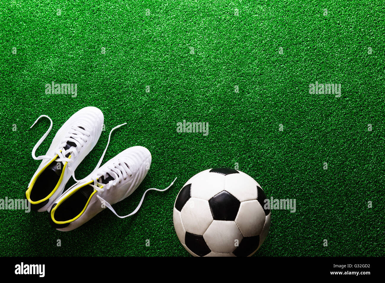 Balón de fútbol y los tacos contra el verde césped artificial, studio sho  Fotografía de stock - Alamy