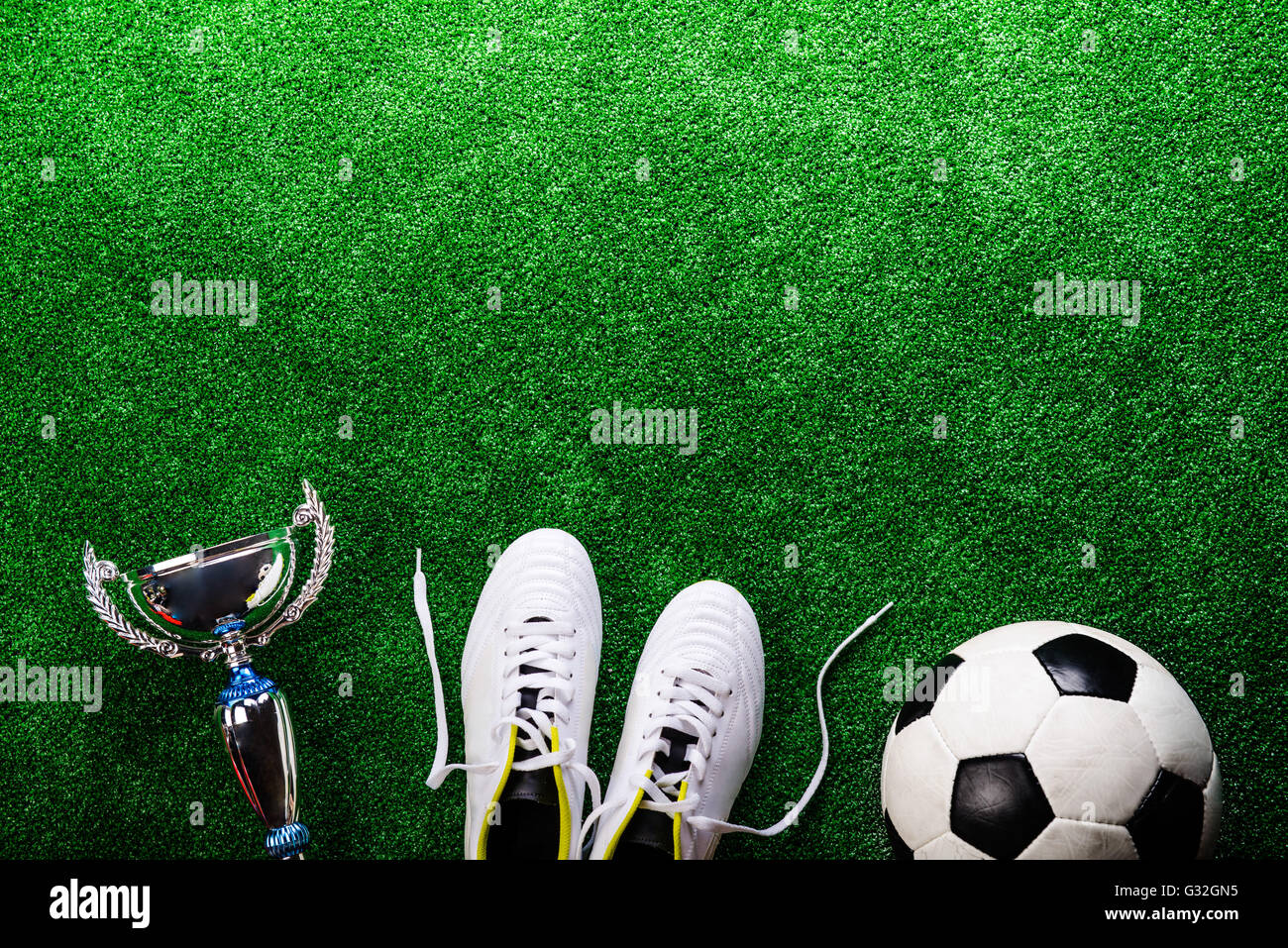 Balón de fútbol, los tacos y el trofeo contra el verde césped artificial  Fotografía de stock - Alamy