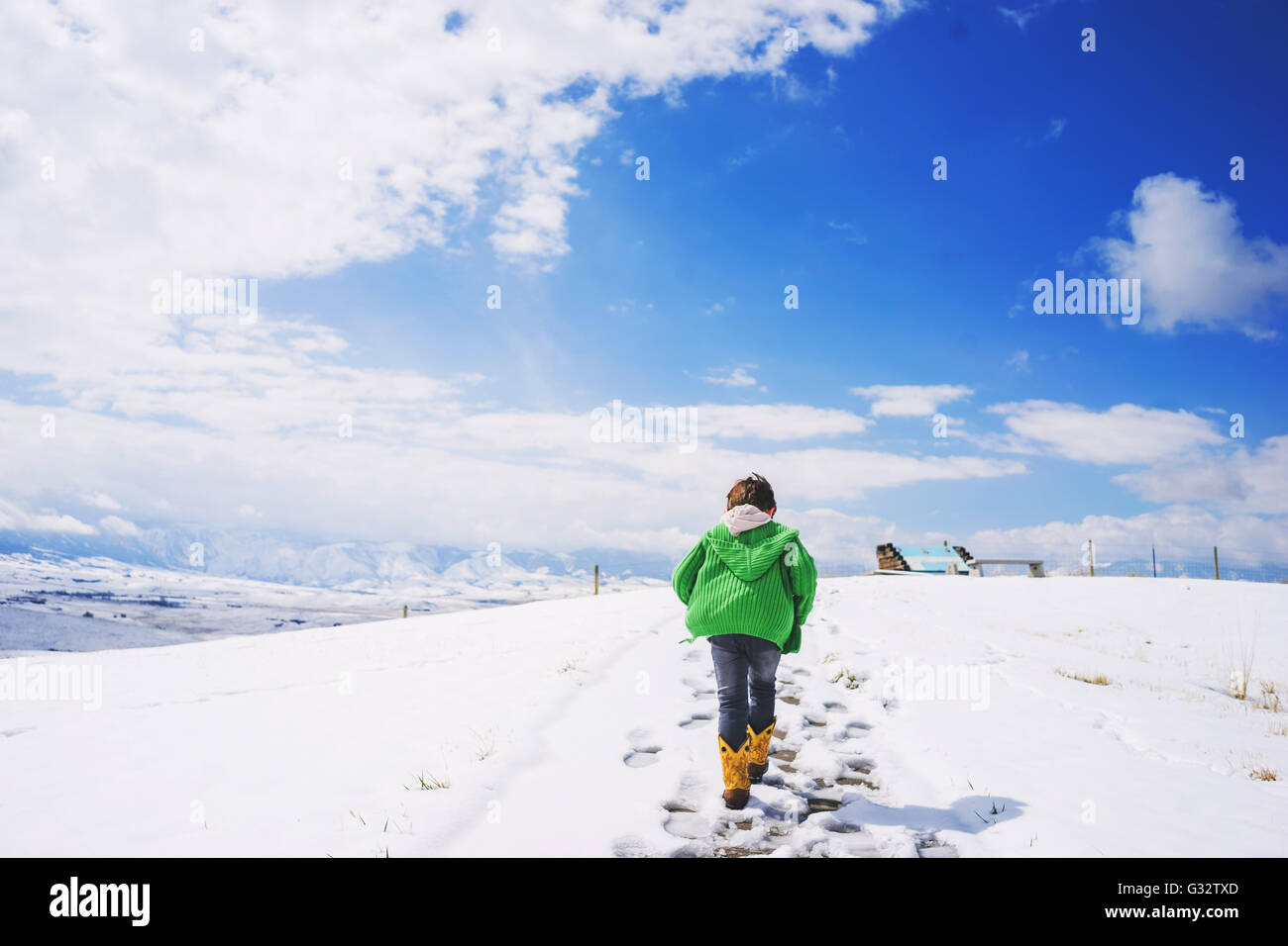 Muchacho caminando cuesta arriba en la nieve Foto de stock