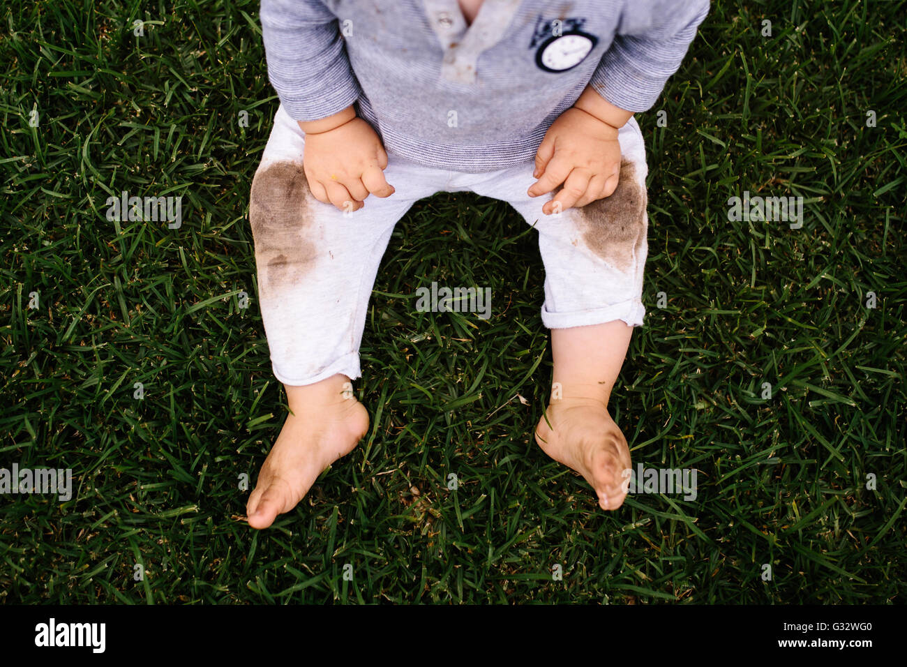 Vista aérea de Baby Boy sentado en la hierba con las rodillas sucias Foto de stock