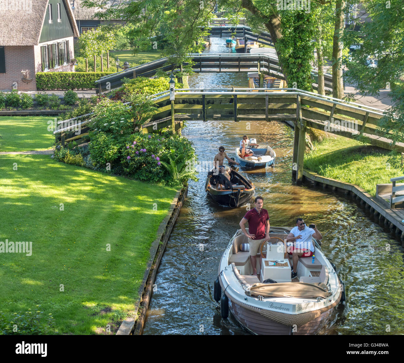 Giethoorn, Países Bajos. Barcos en el canal o la aldea Dorpsgracht con granjas convertidas en islas privadas con puentes. Foto de stock