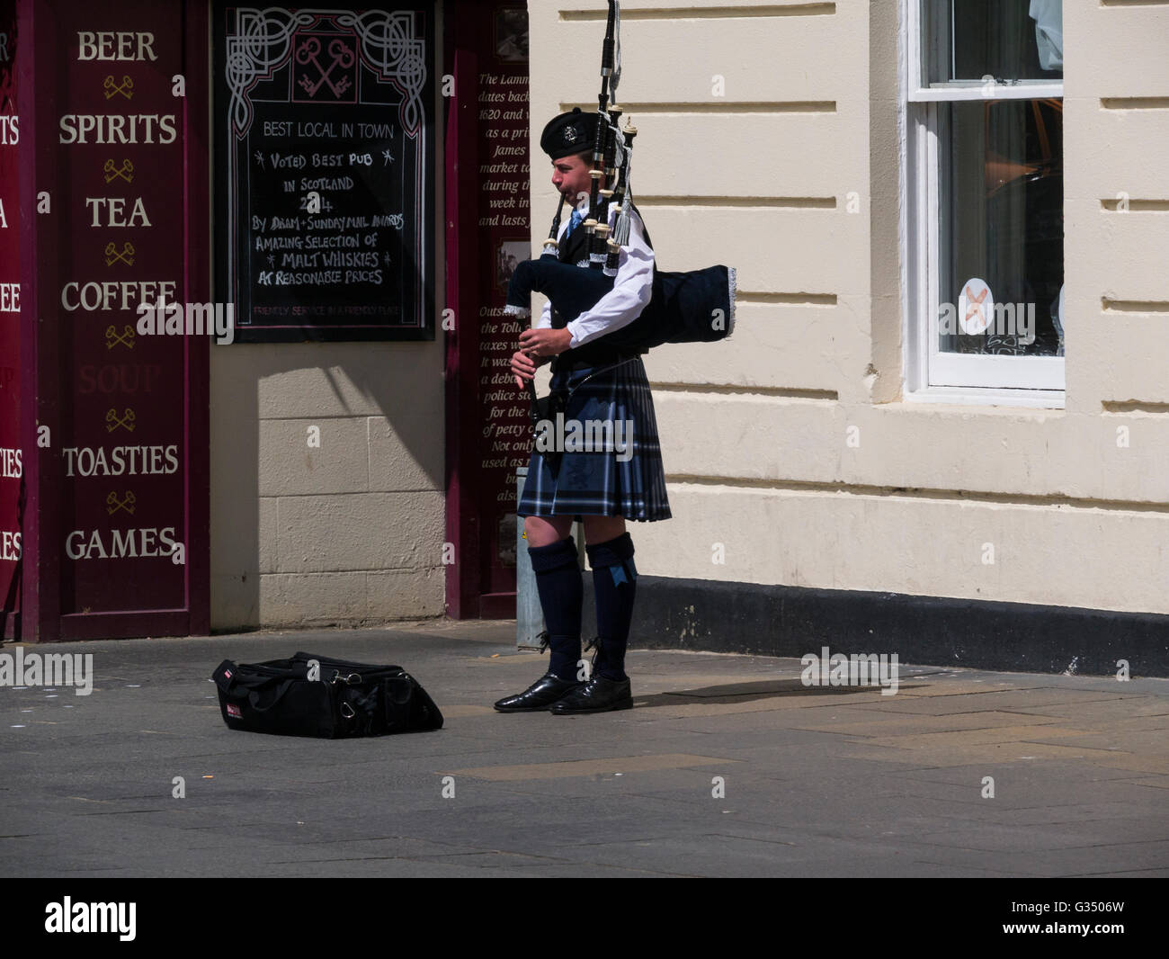 Gaitero escocés tocando la gaita en la calle Royal Burgh de St Andrews Fife, Escocia, en traje nacional escocés tocando canciones Foto de stock