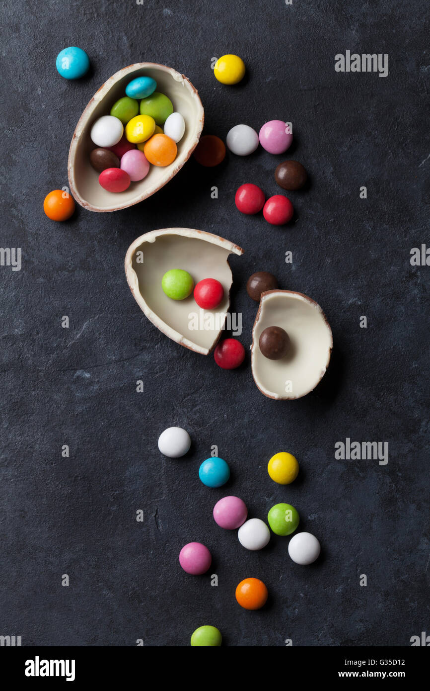 Caramelos de colores y huevo de chocolate sobre fondo de piedra. Vista superior Foto de stock