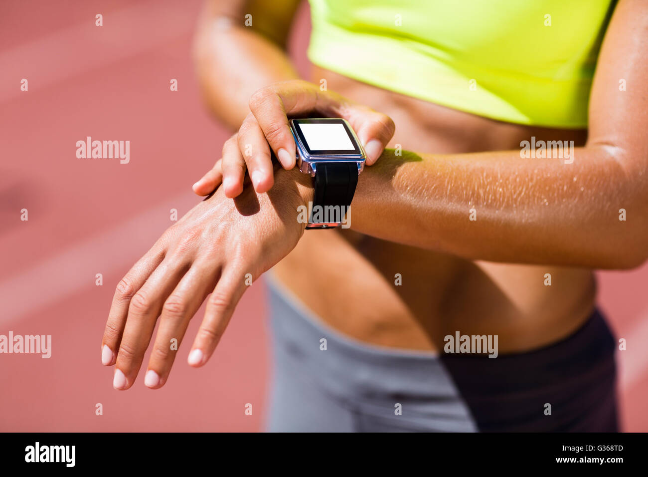 La sección intermedia de la atleta femenina revisando su reloj inteligente Foto de stock