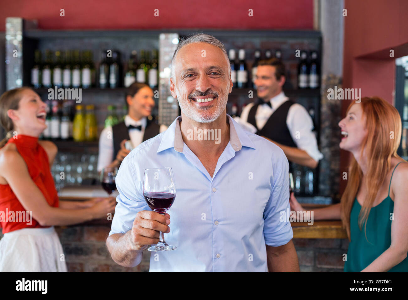 Retrato del hombre sujetando una copa de vino delante del mostrador de bar Foto de stock