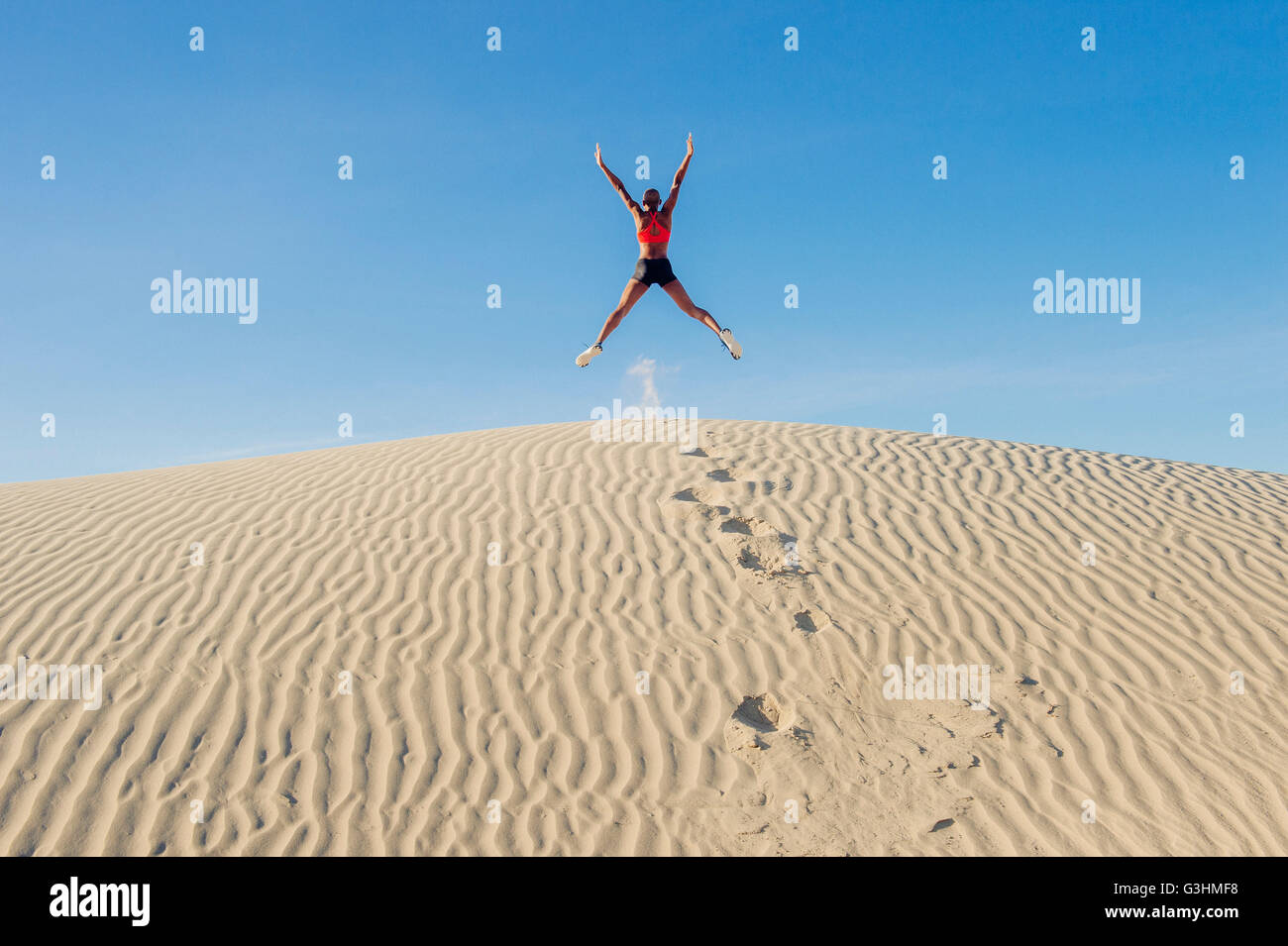 Runner saltando con los brazos y las piernas tendidas en el desierto, el Valle de la Muerte, California, EE.UU. Foto de stock
