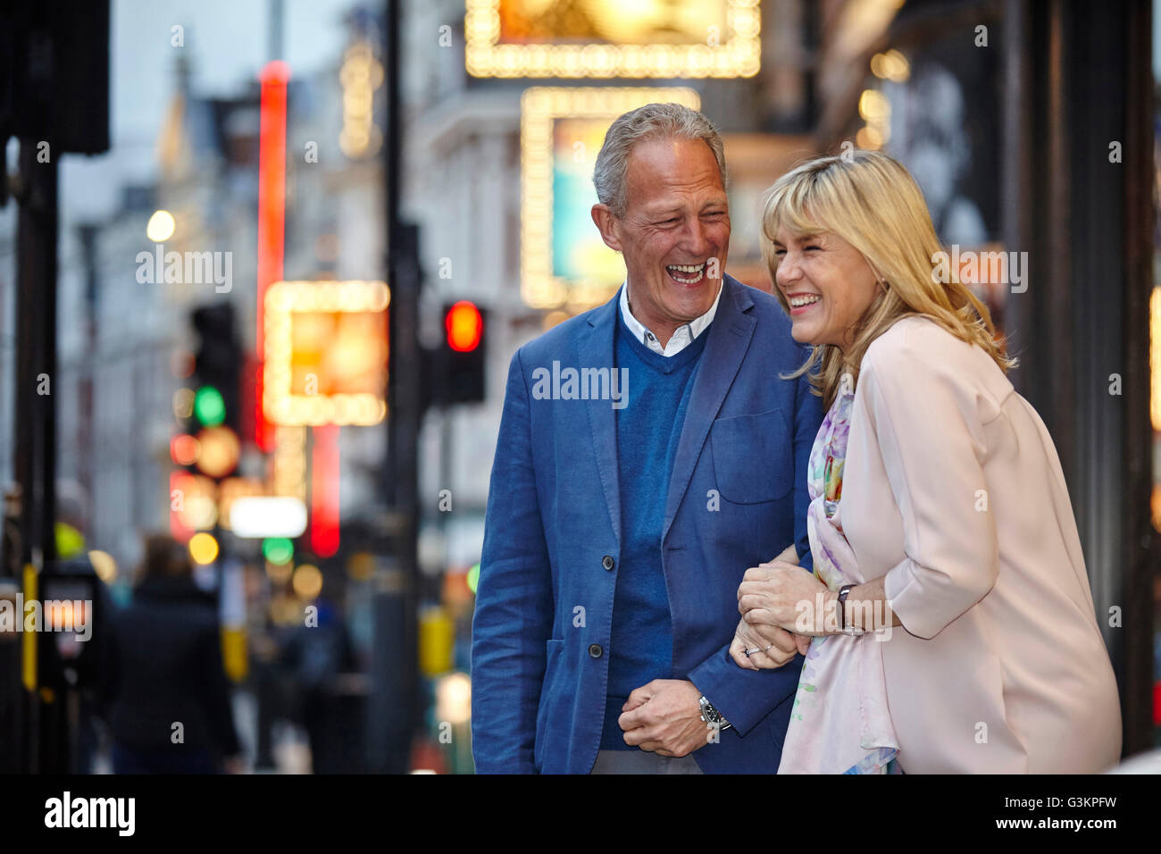 Mature Dating pareja riendo en las calles de la ciudad al atardecer, Londres, Reino Unido. Foto de stock