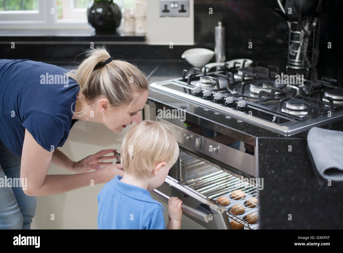 Madre e hijo peeking en horno para comprobar en bicarbonato Fotografía Madre e hijo peeking en horno para comprobar en bicarbonato Fotografía