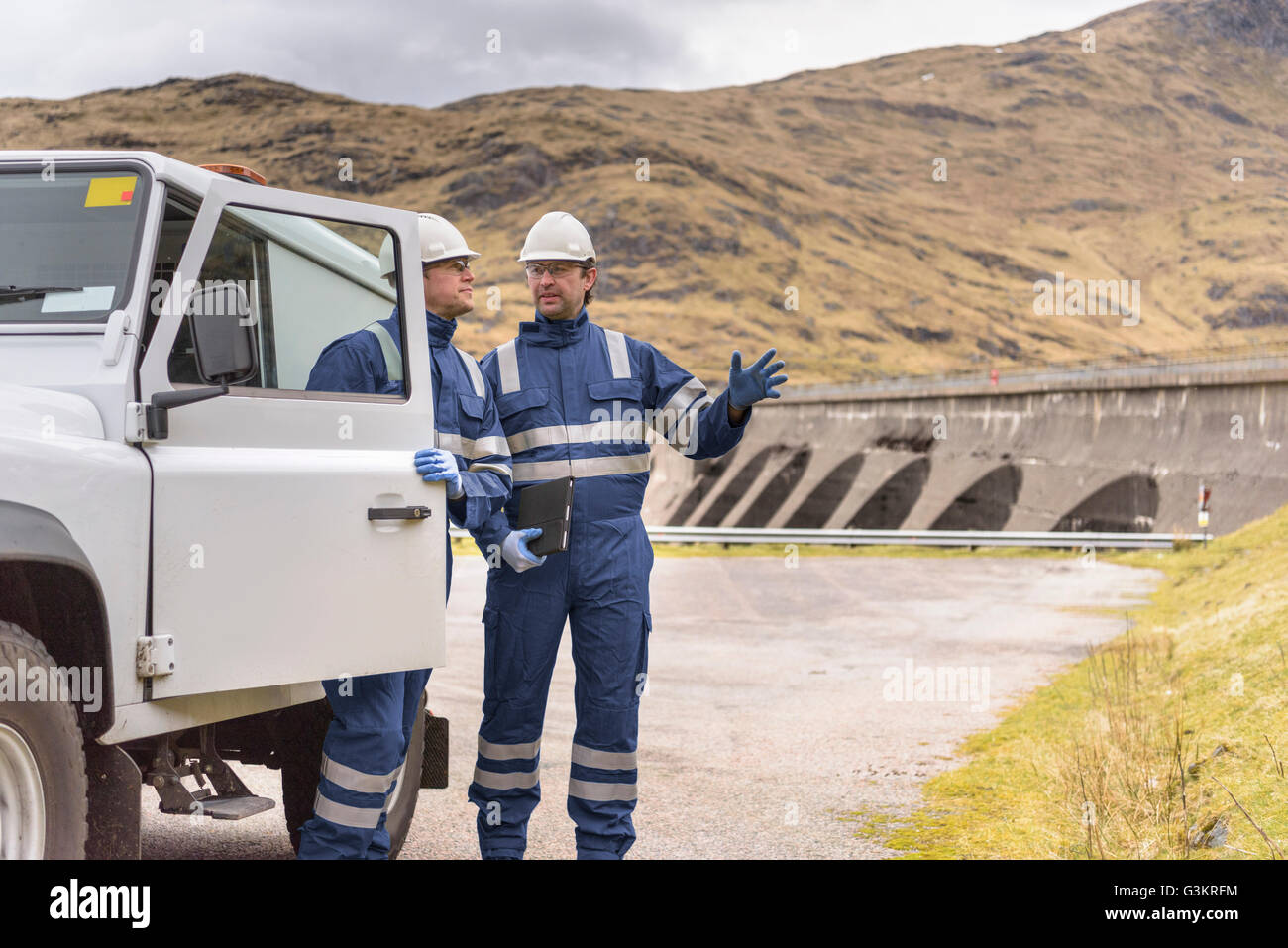Los trabajadores con vehículos utilitarios por dam en la central hidroeléctrica Foto de stock
