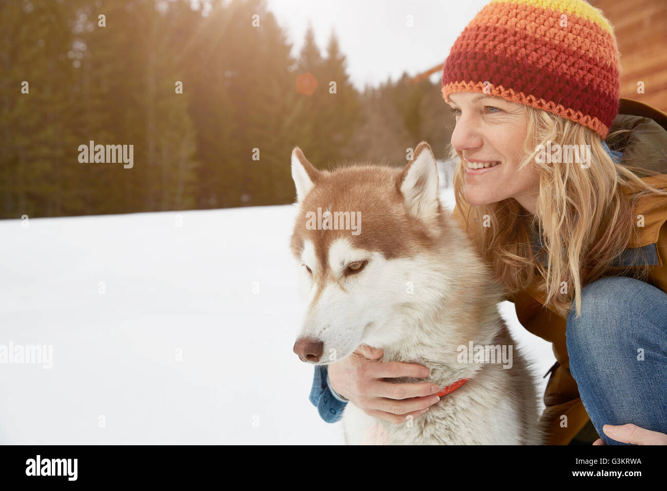 Mujer arrodillada con Husky en el paisaje cubierto de nieve, Elmau, Baviera, Alemania Foto de stock
