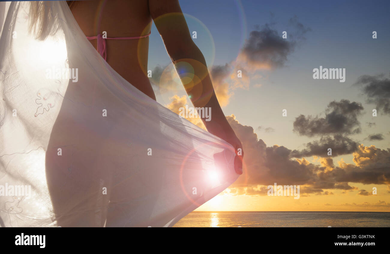 Vista trasera de la mujer joven con bufanda viendo la puesta de sol en Miami Beach, Florida, EE.UU. Foto de stock