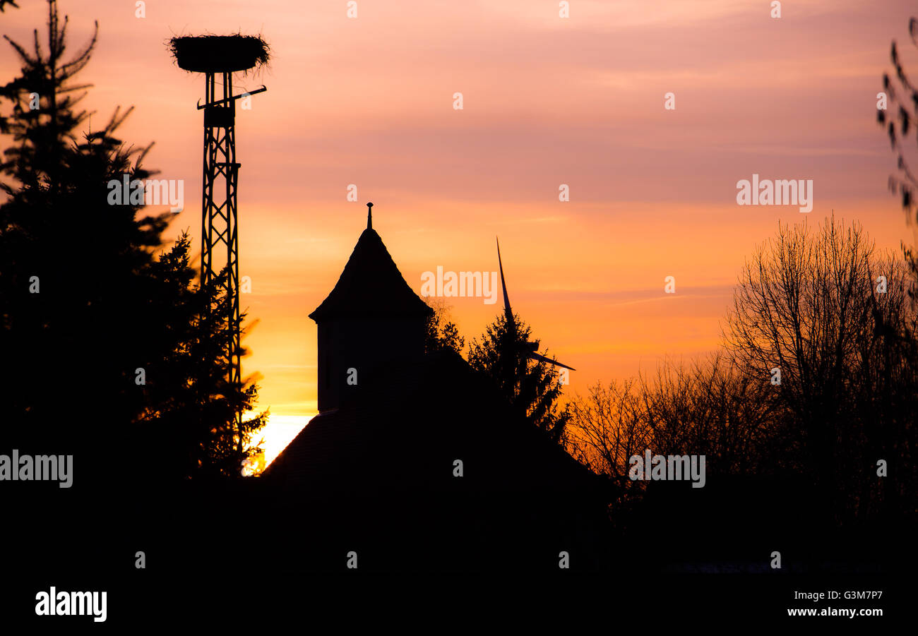 Nidos de cigüeña en la luz del atardecer en el pueblo Foto de stock