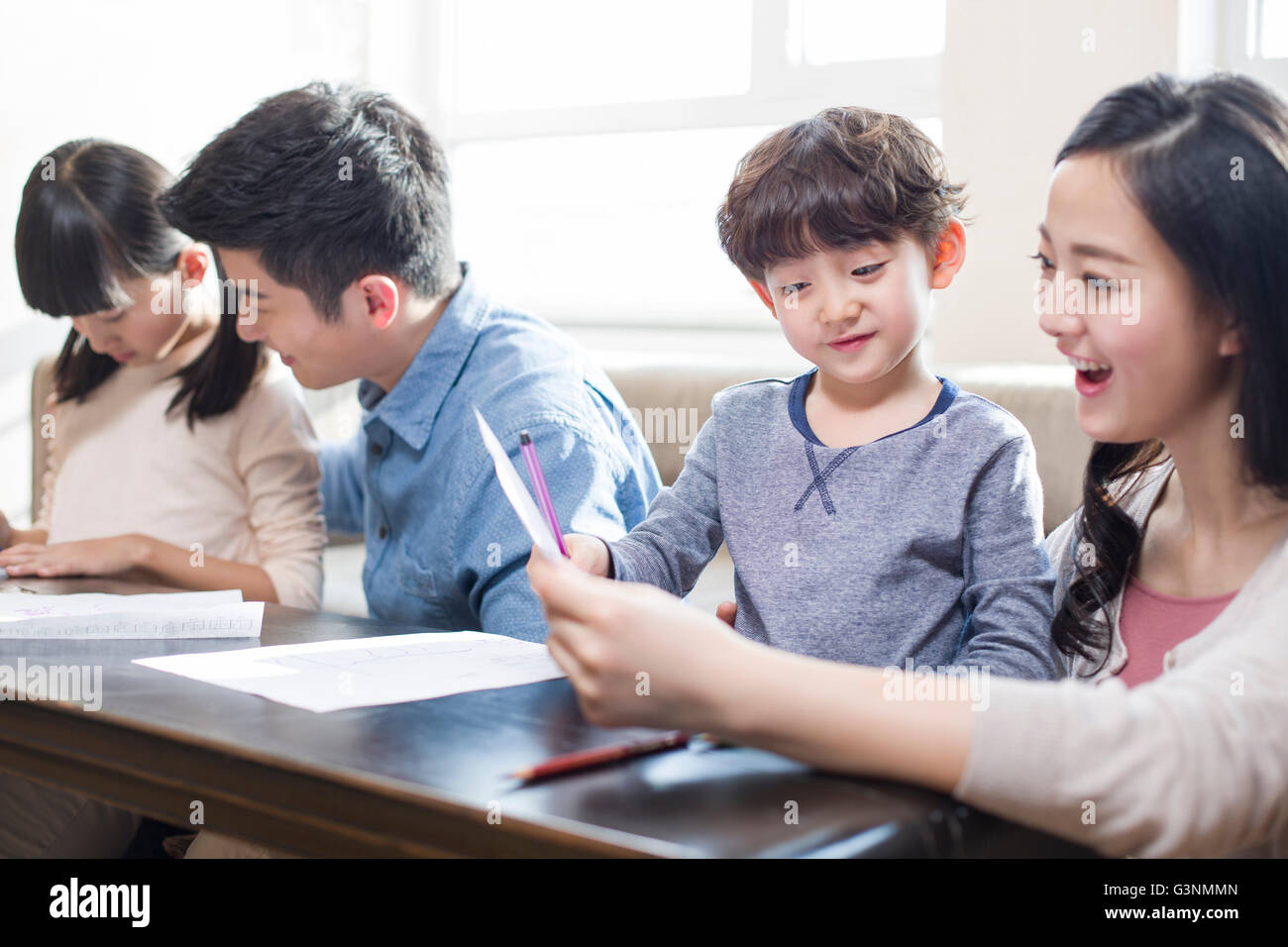 Los padres jóvenes, ayudando a sus hijos con las tareas escolares ...