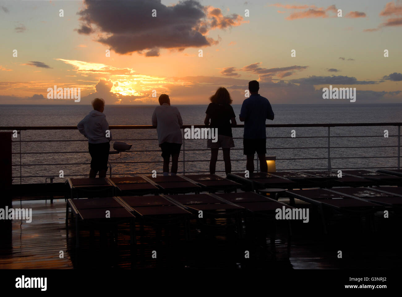 Cuatro personas viendo la puesta de sol en el mar Caribe Foto de stock