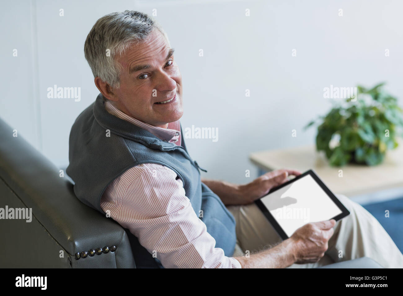 Retrato de altos hombre sentado en el sofá con una tableta digital Foto de stock