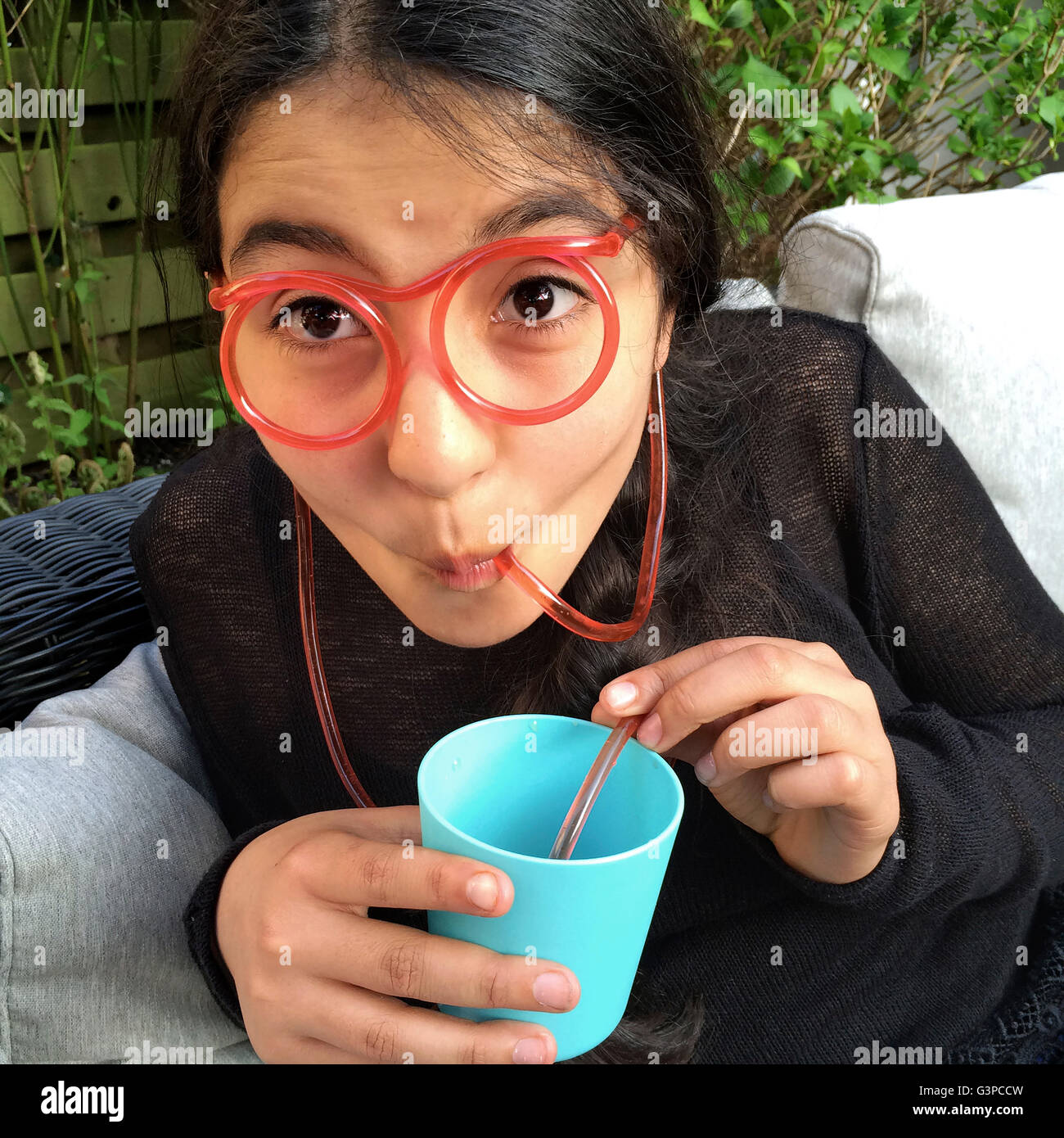Adolescente está bebiendo limonada con un gracioso paja en la forma de gafas Foto de stock
