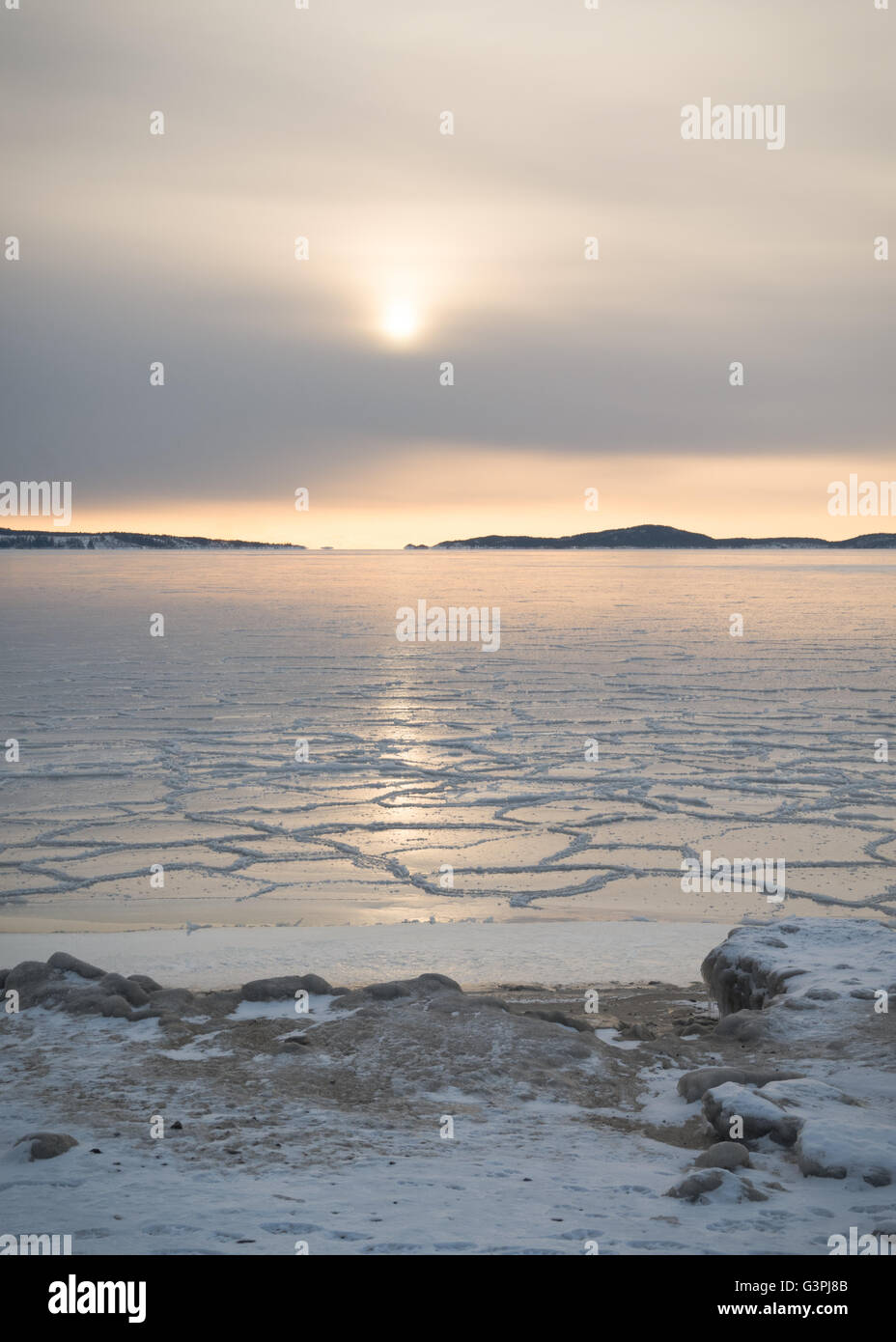 Conjunto bajo sol reflejado en el mar de hielo cerca de la orilla en el archipiélago fuera de Örnsköldsvik en la parte septentrional de Suecia Foto de stock