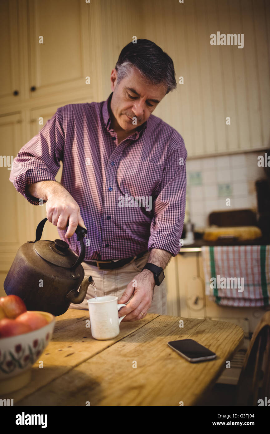 Hombre maduro, llenando su taza de agua caliente Foto de stock