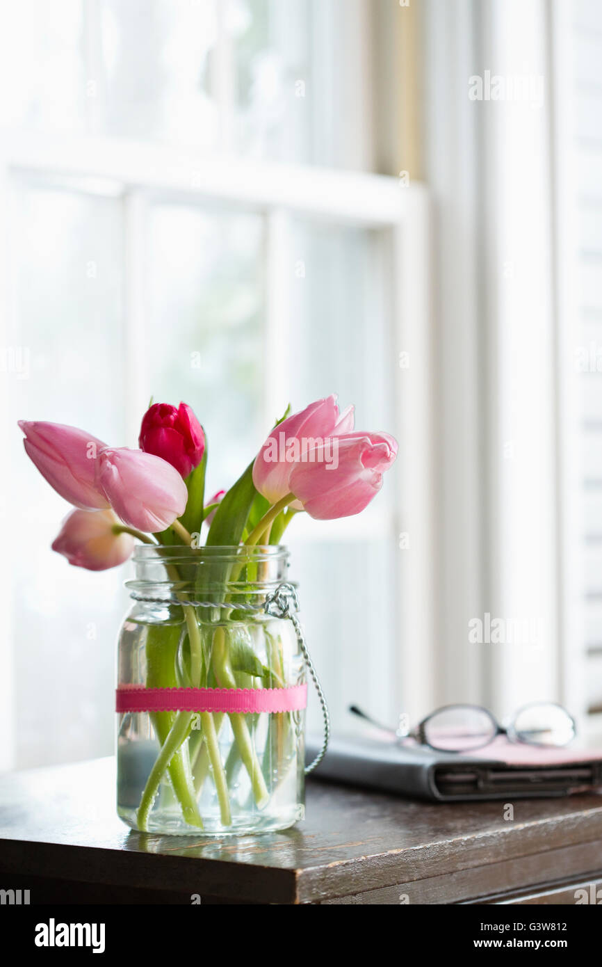 Tulipanes rosas en un jarrón sobre la mesa de noche Foto de stock