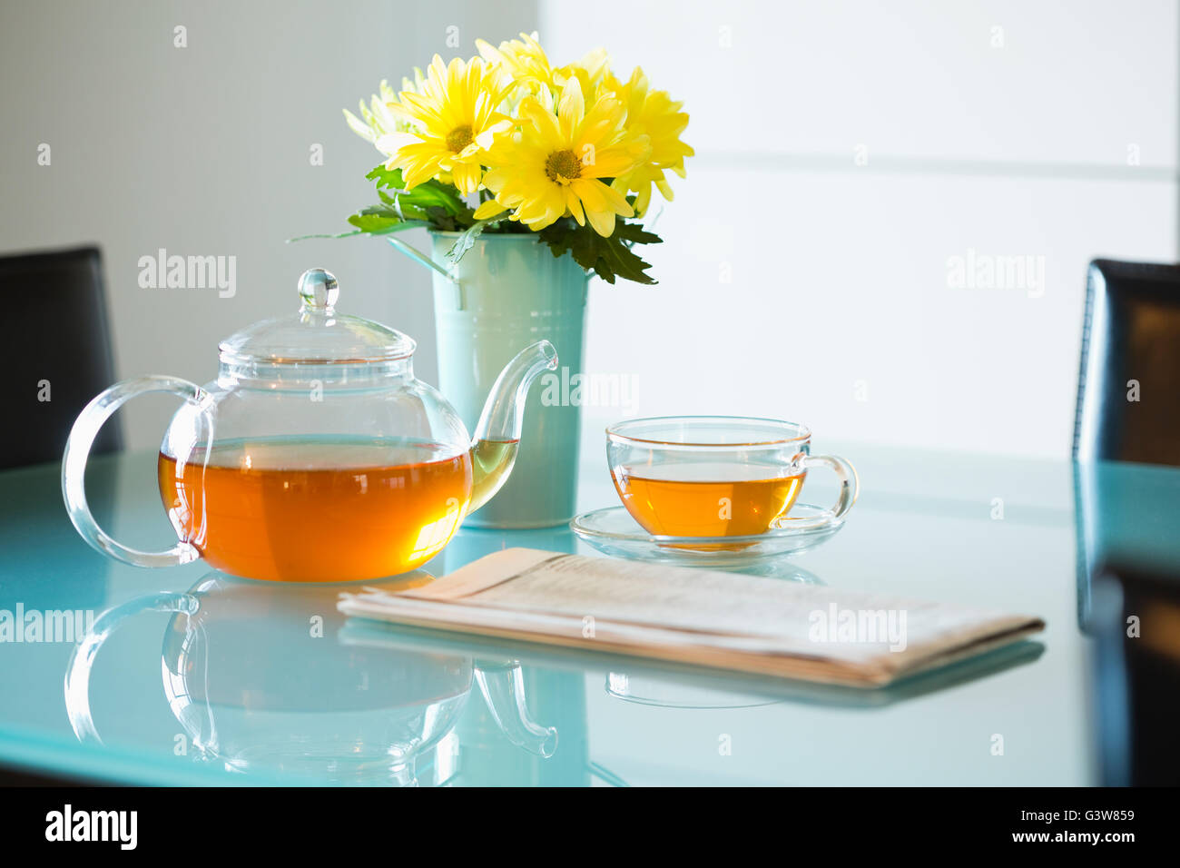 Té con tetera y bouquet de margaritas amarillas en la tabla Foto de stock