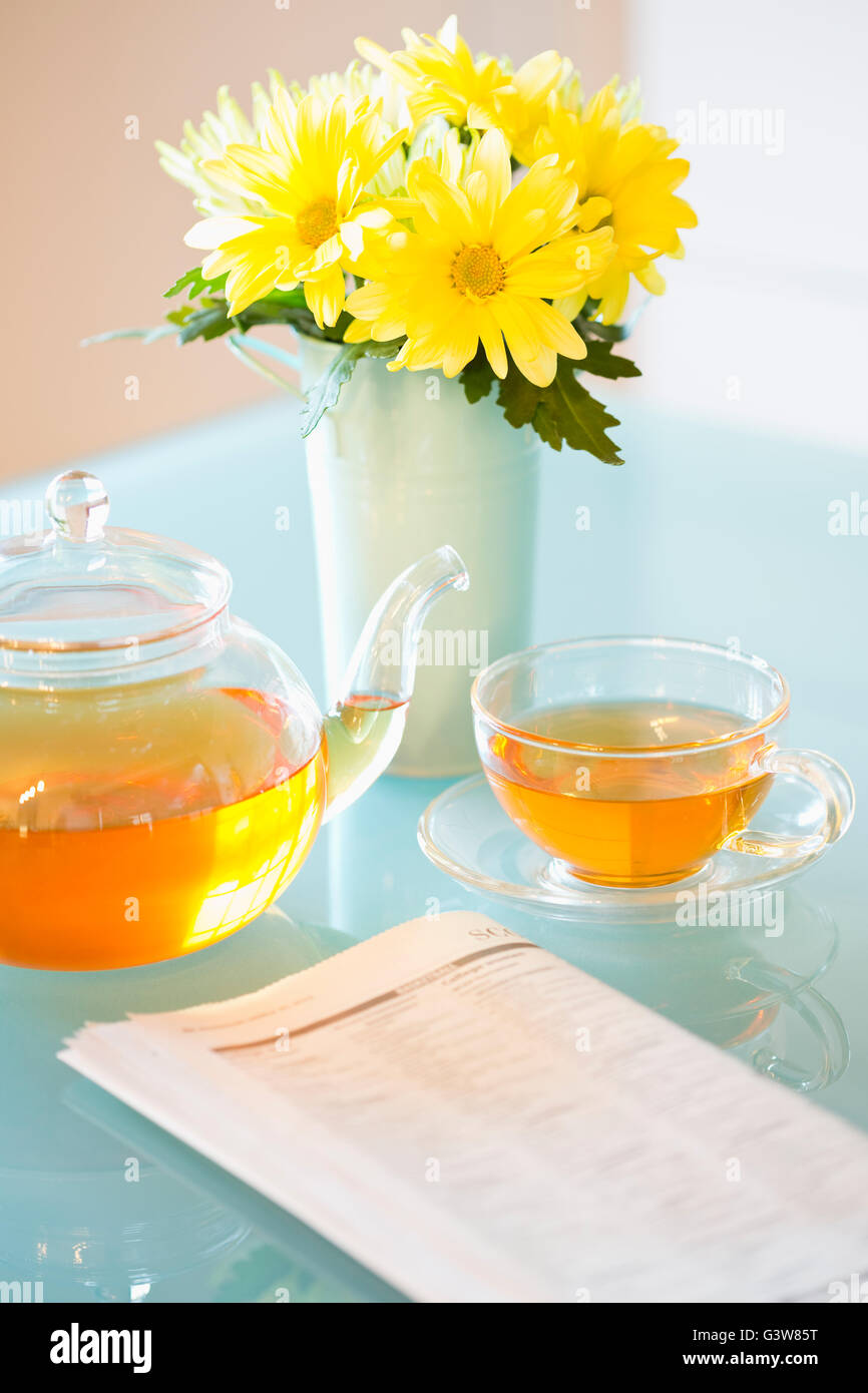 Té con tetera y bouquet de margaritas amarillas en la tabla Foto de stock