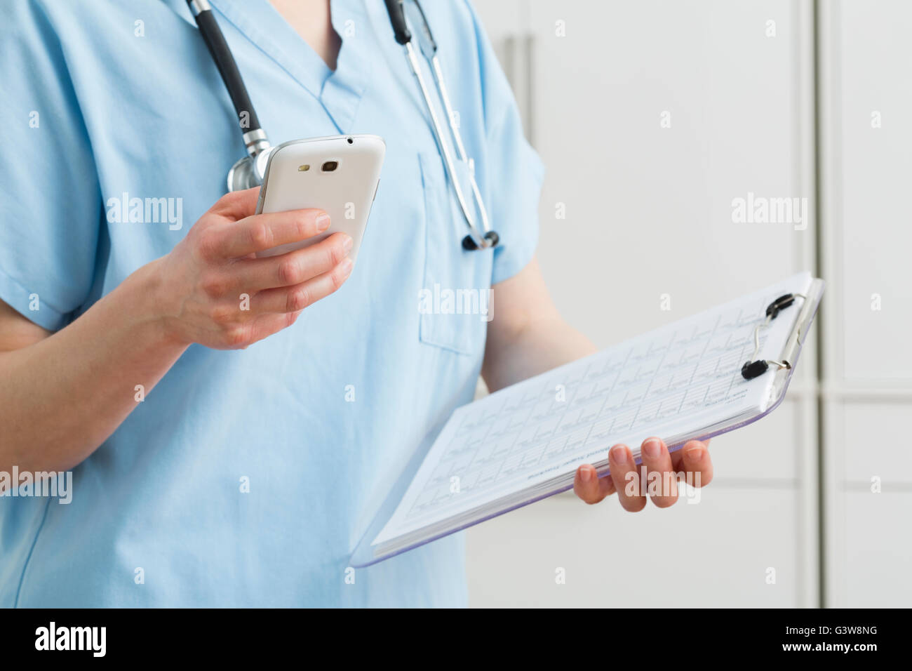 Enfermera la celebración de smart phone y registros médicos Foto de stock