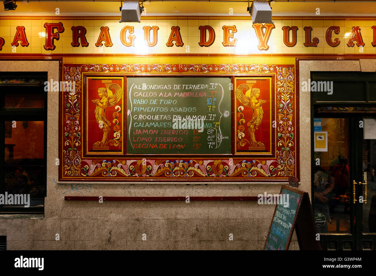 La Fragua de Vulcano restaurante con fachada de azulejos ornamentados y menú, Madrid, España Foto de stock