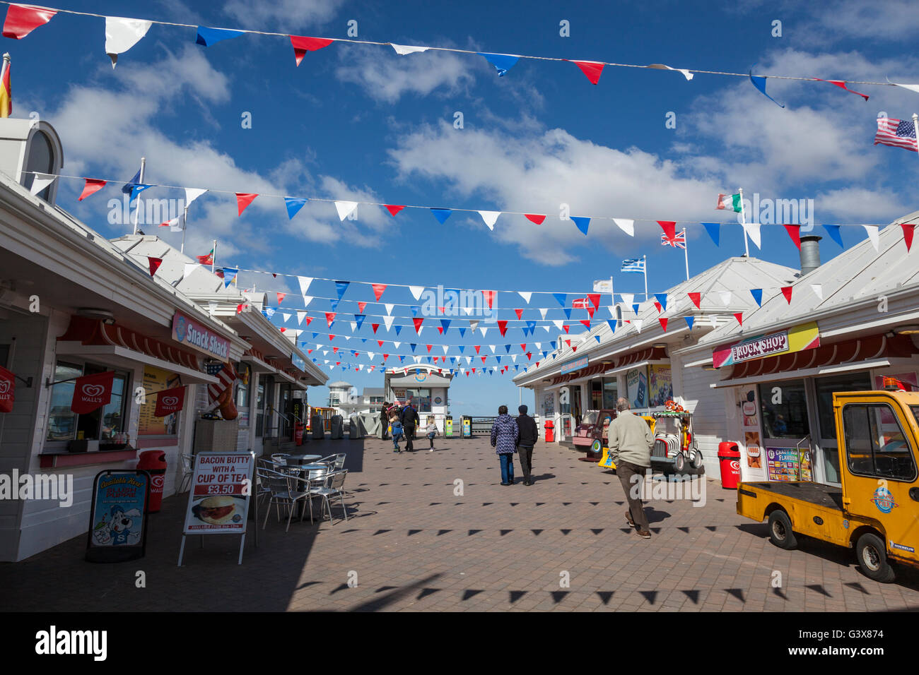 Banderas y Bunting, contrastados con un cielo azul en la entrada de la