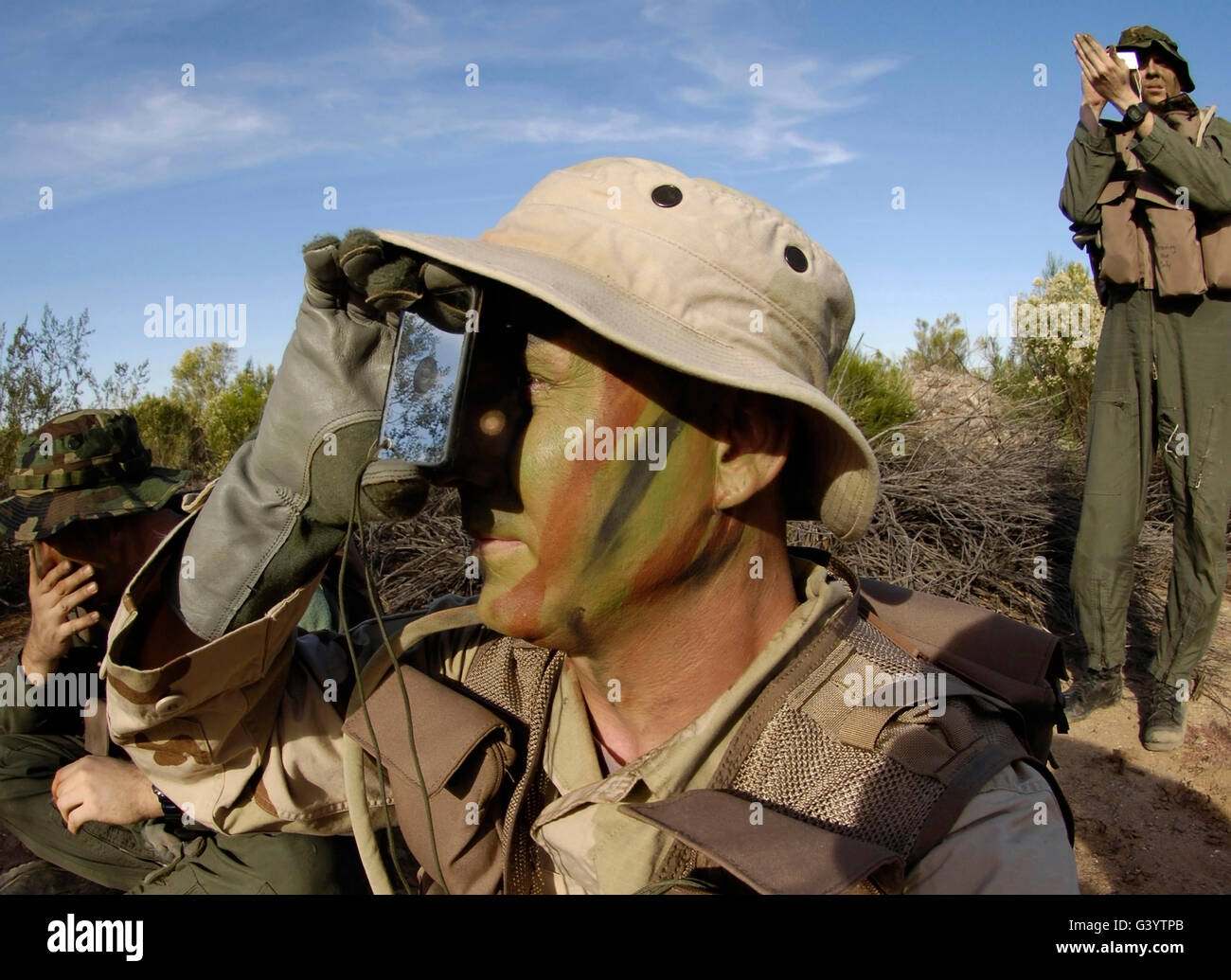 Un soldado utiliza una señal espejo durante un curso de supervivencia de combate. Foto de stock