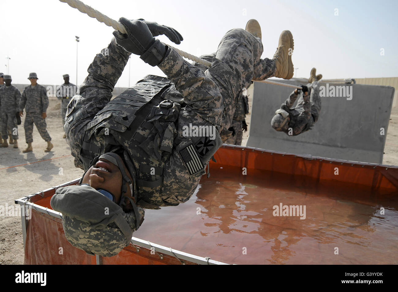 El especialista del ejército usa una cuerda de 15 pies para cruzar un obstáculo de agua. Foto de stock