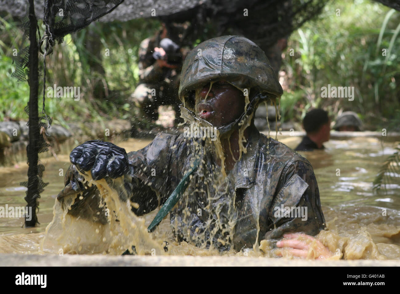 Un Marine salpica como él hace su manera a través de una carrera de obstáculos en el Centro de Entrenamiento de Guerra en la selva. Foto de stock