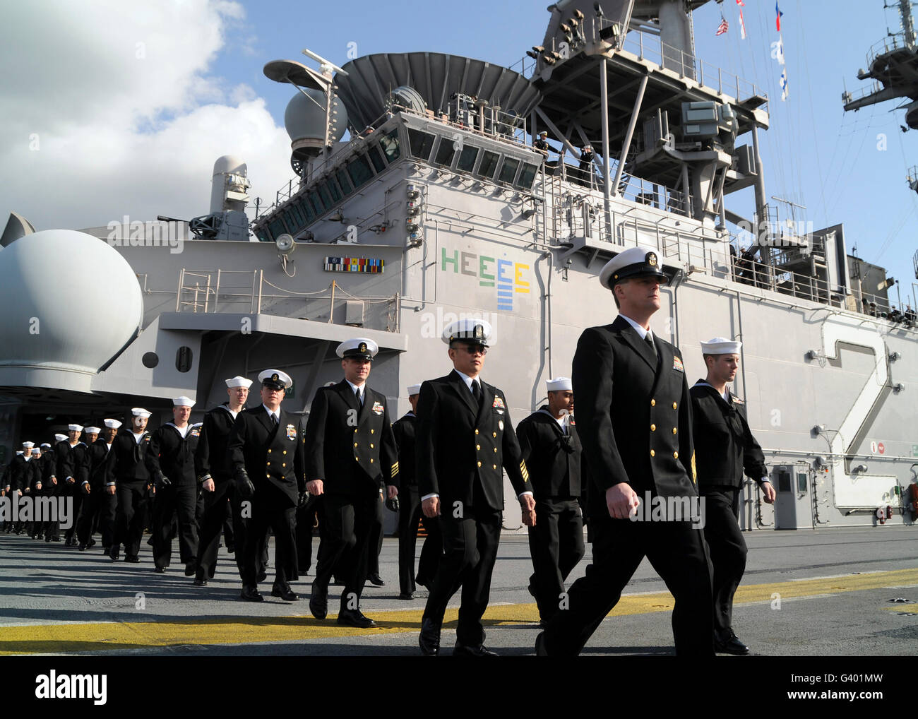 La tripulación del USS Essex marchas hacia la cubierta de vuelo para el hombre los rieles. Foto de stock