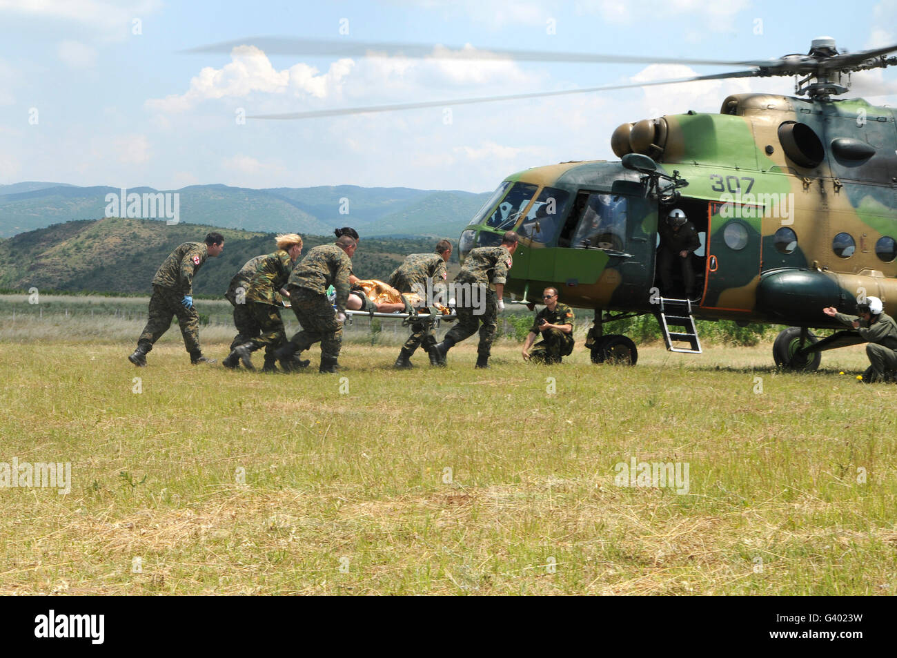 Personal médico lleve un paciente herido a un helicóptero Mi-17. Foto de stock