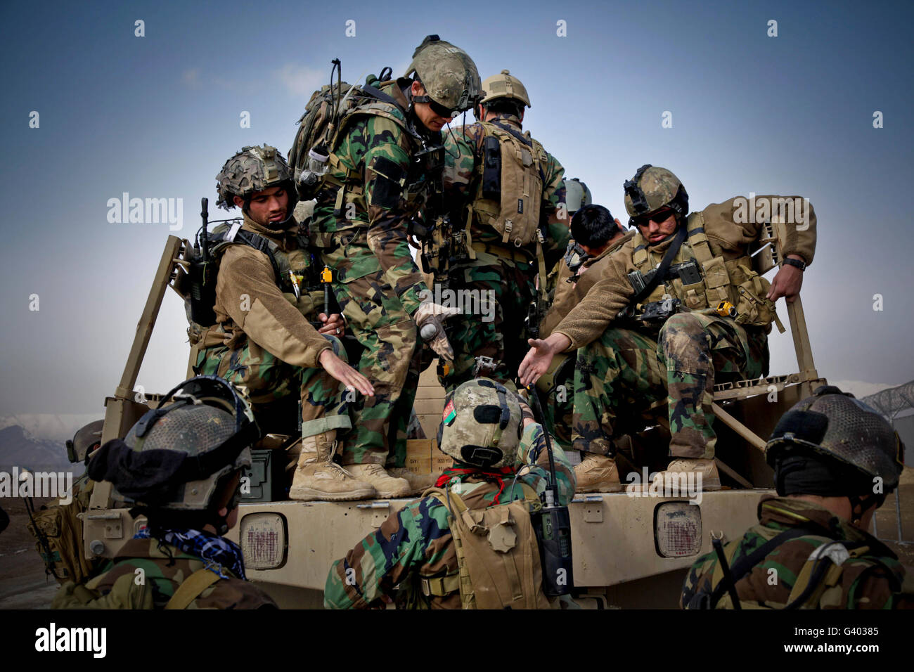 Los soldados afganos dan una mano hasta un soldado compañero. Foto de stock