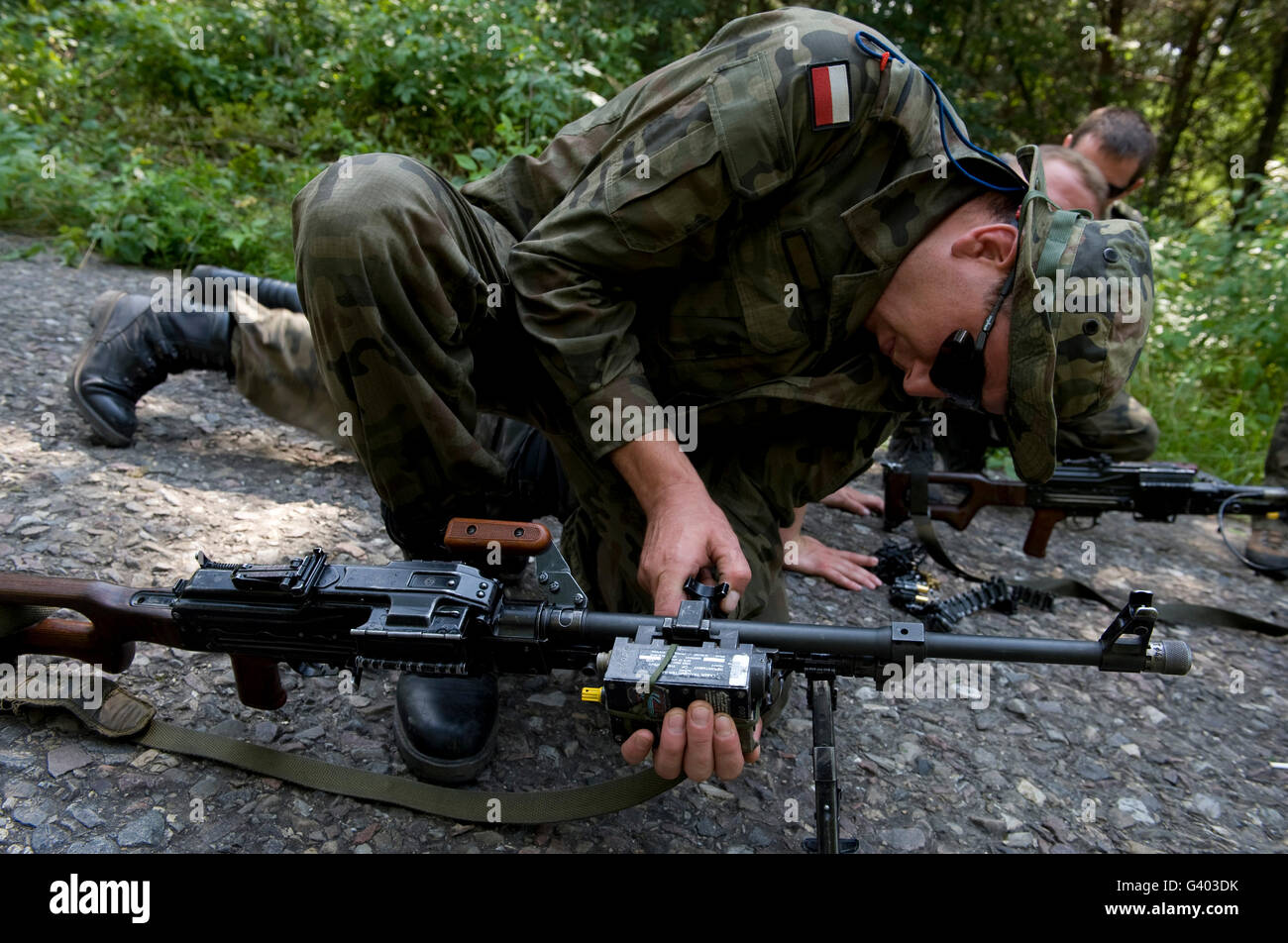 Un soldado polaco atribuye un dispositivo de entrenamiento a su ametralladora PKM. Foto de stock