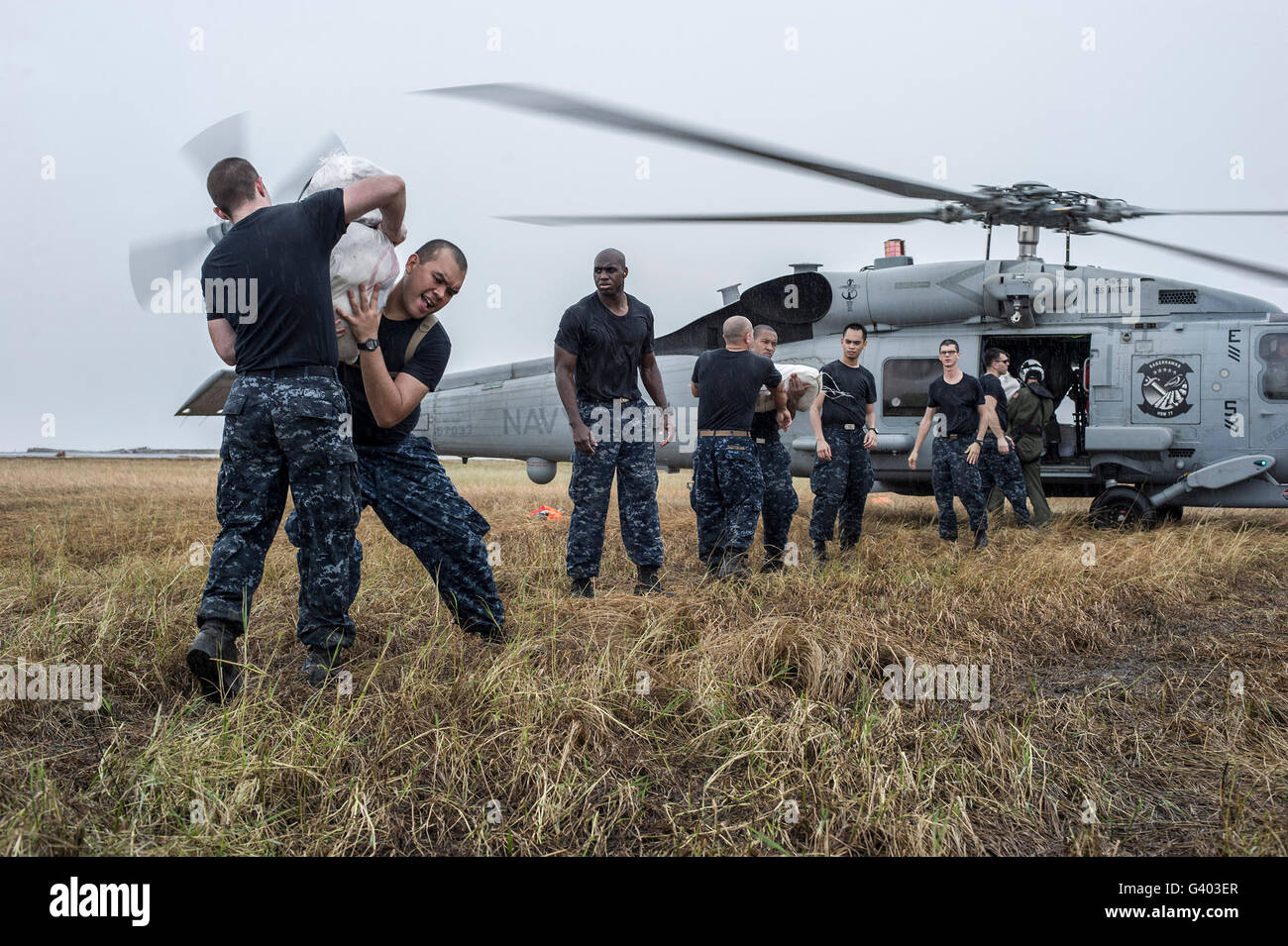 Los marineros cargar suministros de socorro a un MH-60R Sea Hawk helicóptero. Foto de stock
