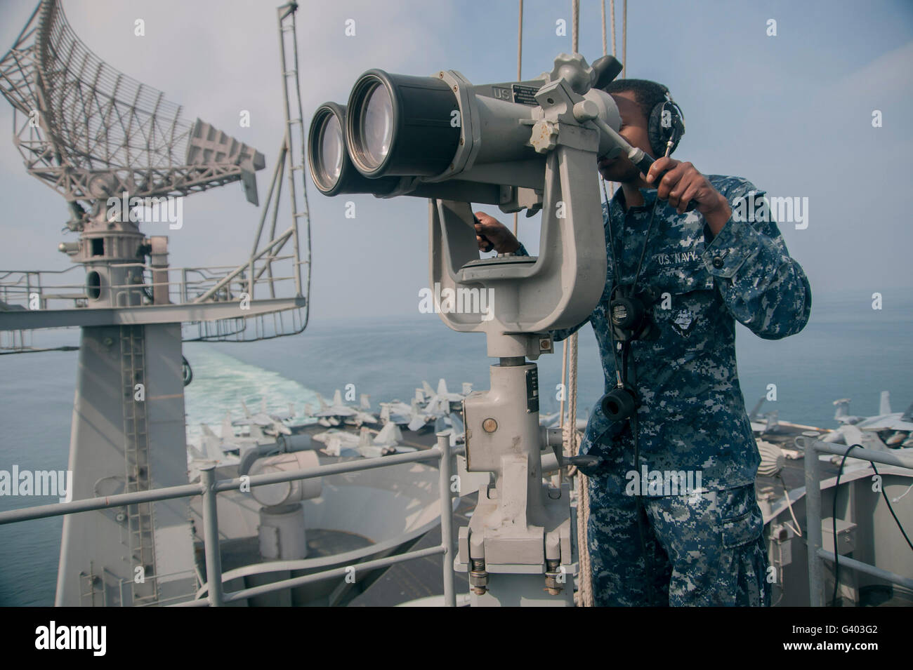 Especialista en operaciones marinero mira a través de binoculares de alta potencia. Foto de stock