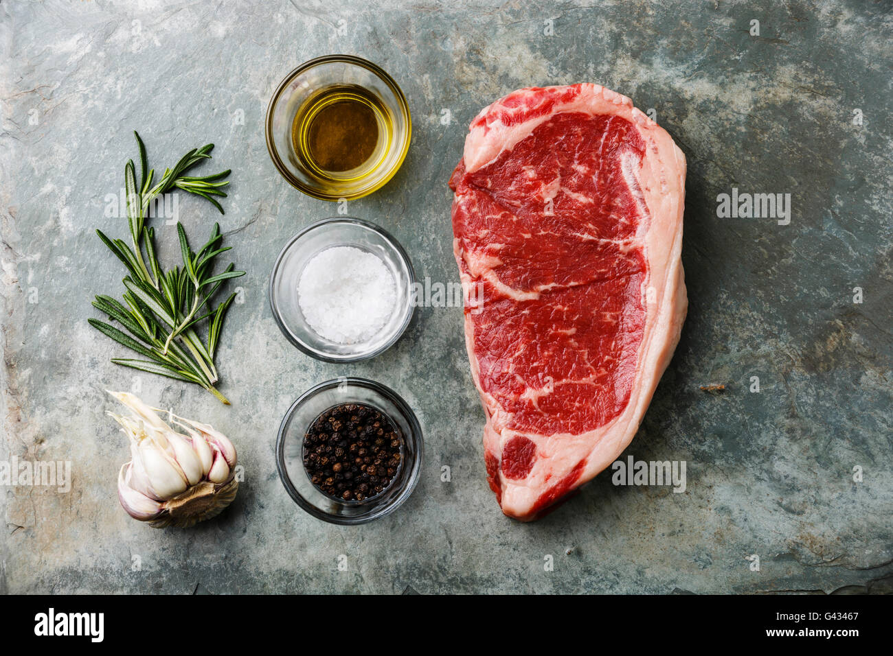 Carne fresca cruda bistec de solomillo con romero, aceite para cocinar, sal  y pimienta sobre fondo de pizarra de piedra Fotografía de stock - Alamy