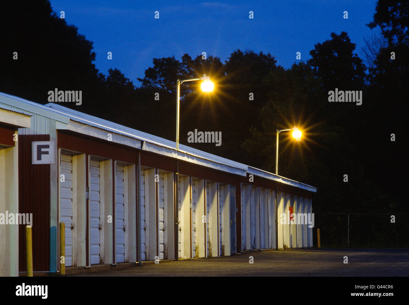 Vista de noche de garaje como unidades de almacenamiento alquiler alineadas en una fila Foto de stock