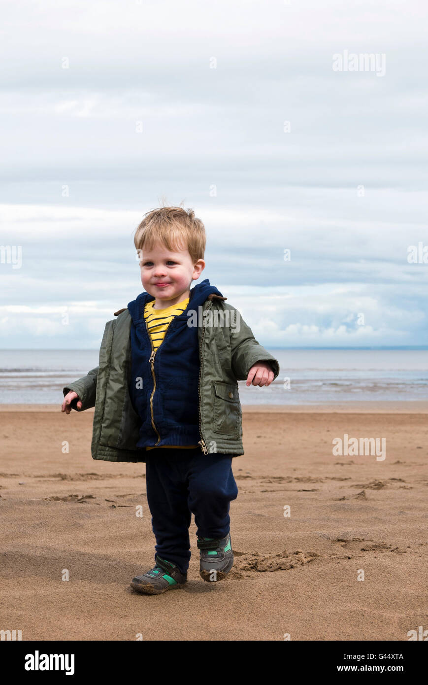 Joven jugando en la playa en Minehead (Somerset, Reino Unido) en un día ventoso y frío Foto de stock
